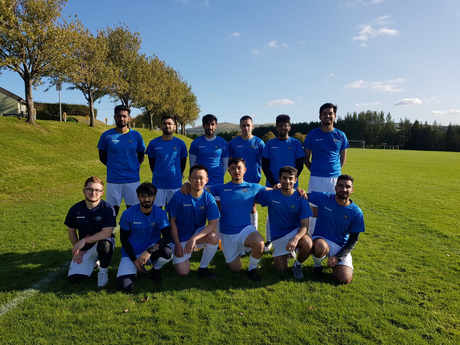 Ihsan Youth FC players in blue football kits together on the pitch